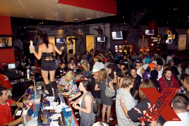 Go-go dancers performing on raised platforms above a packed XTREME crowd and bar