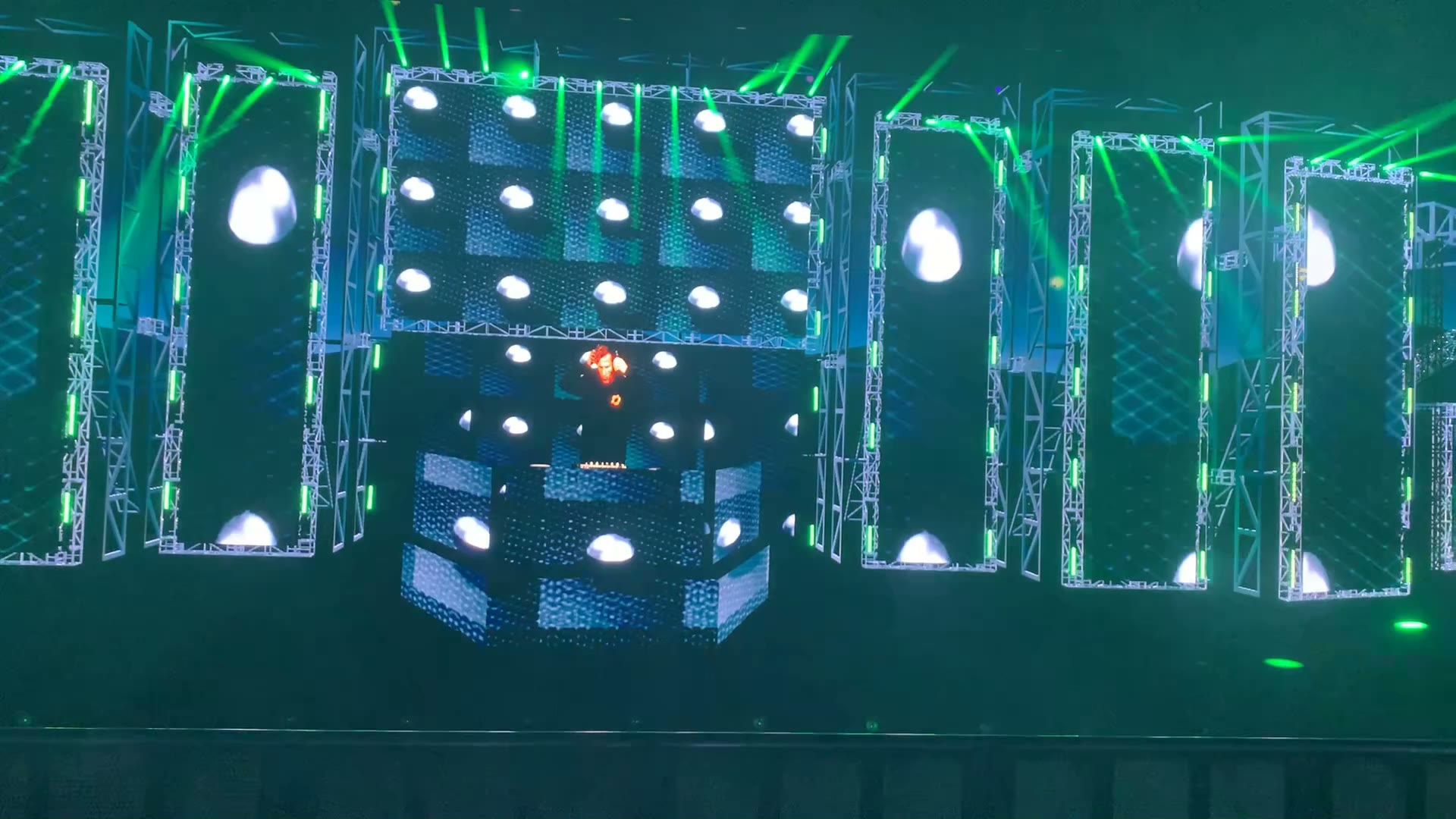 Animated virtual stage with green lighting, circular screen content, and side LED walls