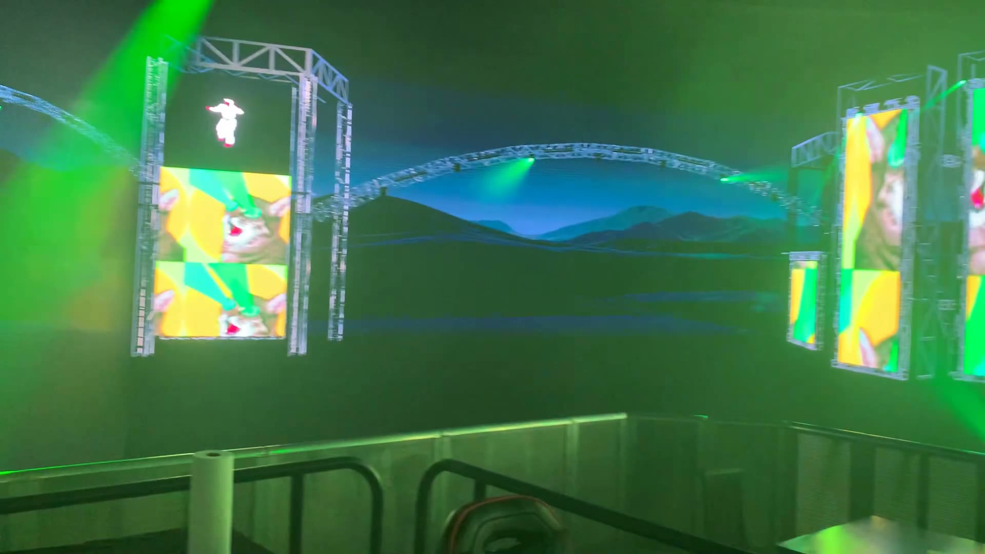 Side view of the virtual stage showing colorful LED walls, rails, and blue landscape environment